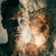 A conceptual double-exposure photo showing a young adolescent's face blended with a cracked, weathered wall texture, symbolizing political alienation and disillusionment. The left half reveals the youth's serious expression while the right dissolves into fractured, peeling surfaces, visually representing distrust, powerlessness, and psychological fragmentation associated with the pathway from system-disillusionment toward political radicalism in Swedish adolescents.