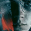 A photo showing a fragmented, close-up human face in muted blue-gray tones, overlaid with distorted textures and streaks of vivid red. The image is heavily manipulated with cracked, glass-like fractures and double-exposure effects that obscure the eyes, evoking themes of psychological rupture, obscured identity, and violence—visually paralleling the article's discussion of ideology-free extremism fixated on aggression itself.